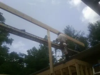 Carpenter setting a ridge beam over a new addition frame — Ice Dam Removal by Roofing Brothers in Clarkrange