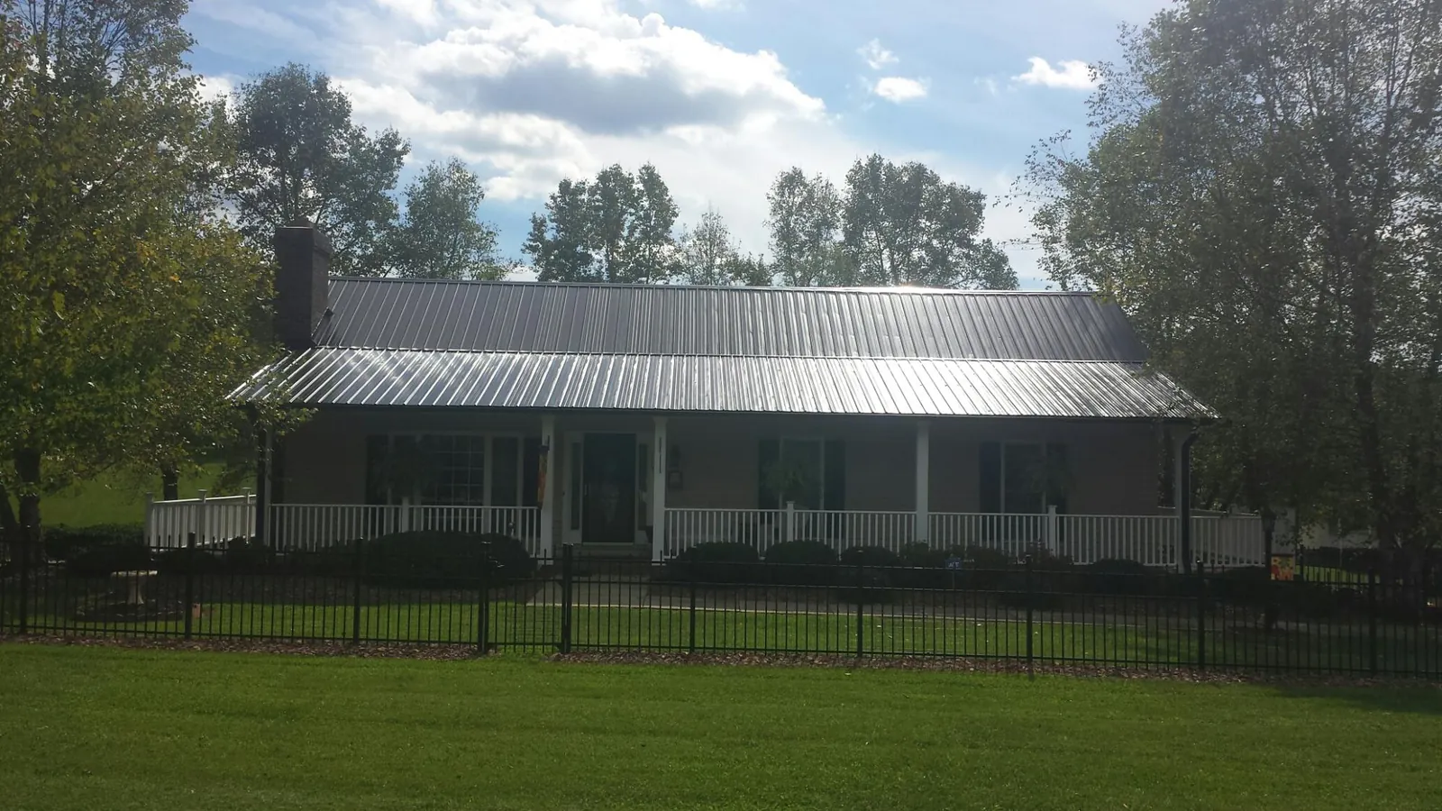 Gray metal roof on a brick ranch with a full width front porch — Gutter Guard Installation work by our crew in Clarkrange