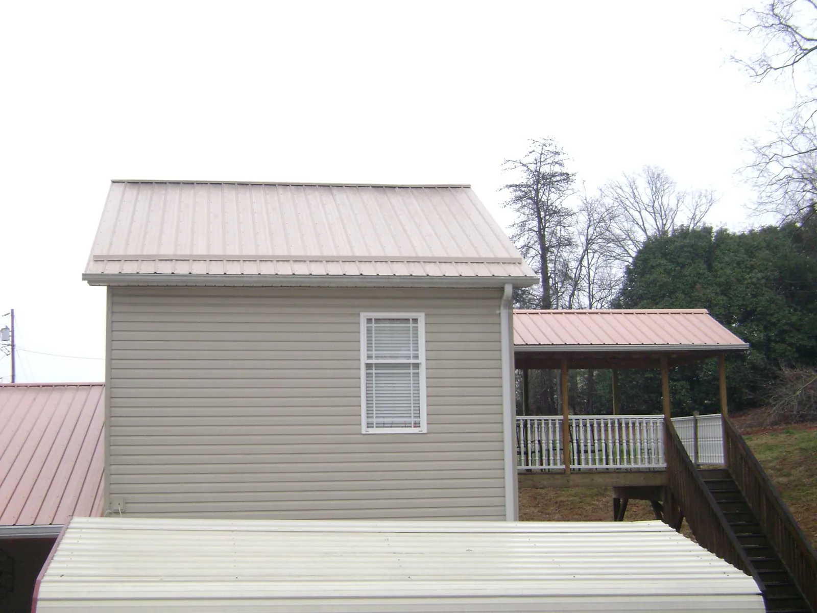 Tan metal roofs on a two story addition and attached porch, from a Roof Replacement job in Clarkrange
